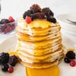stack of pancakes topped with fruit and syrup