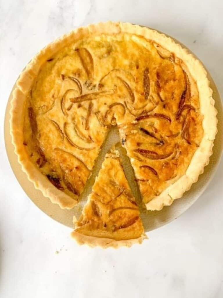 cheese tart with a slice cut into it on a white surface