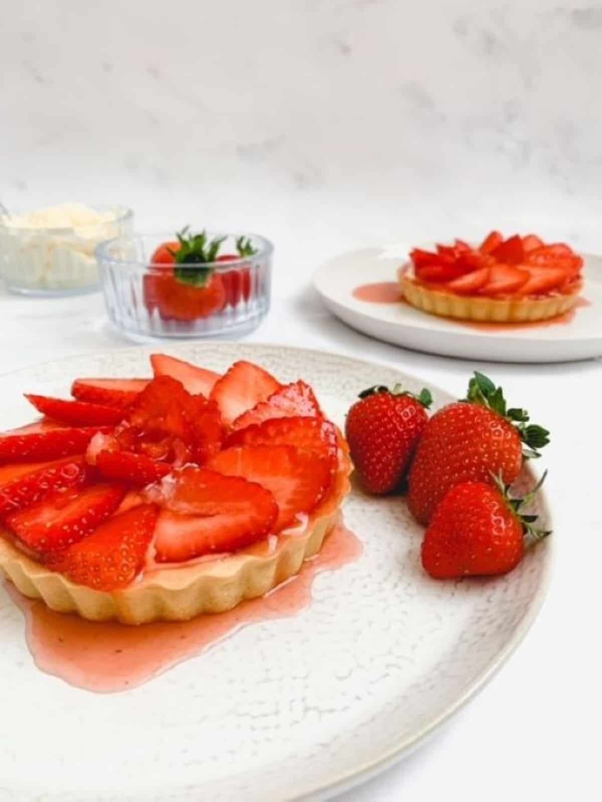 strawberry tart on a white plate with fresh strawberries on the side