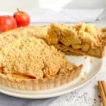 Gluten free apple crumble tart with a slice being lifted out of the pie