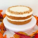 gluten free pumpkin cake on a white cake stand surrounded by autumn leaves