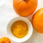 pumpkin puree in a bowl beside two sugar pumpkins