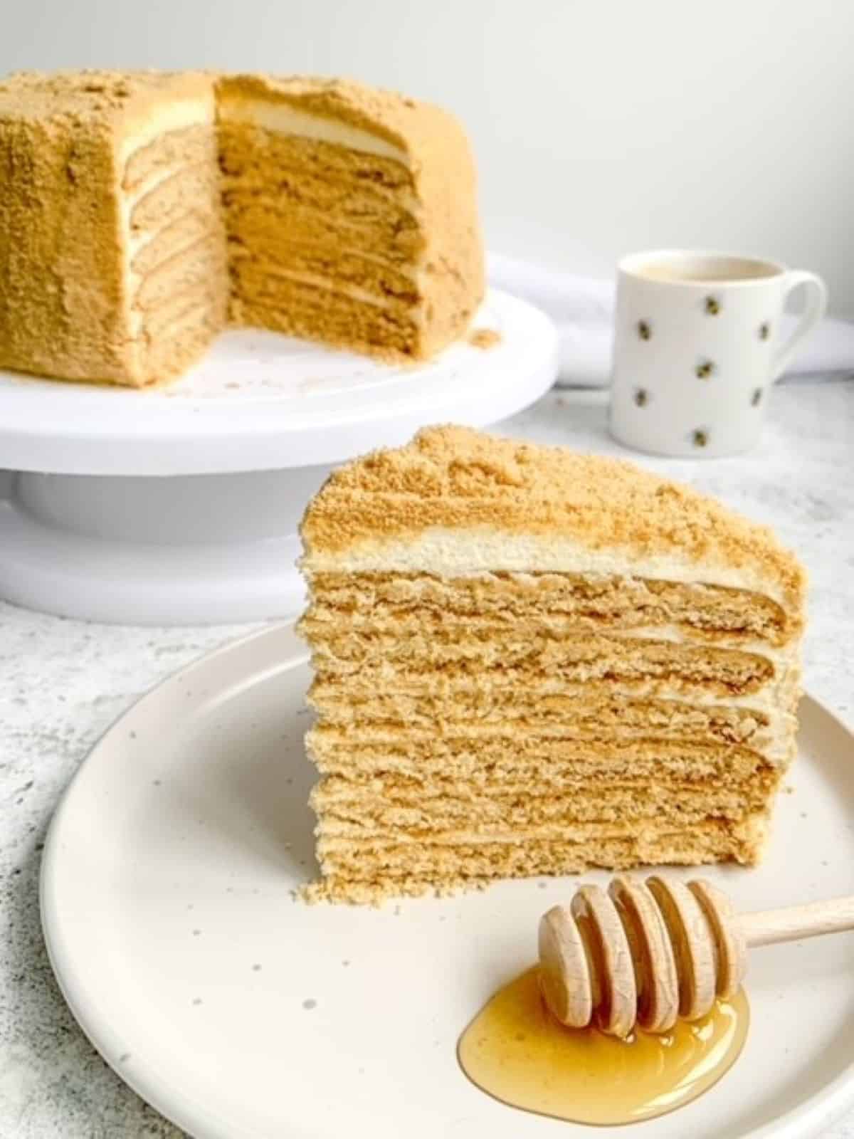 medovik tort on a cake stand with a slice of cake on a white plate