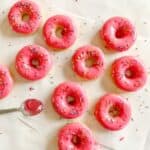Simpson donuts on a white surface beside a spoon of icing