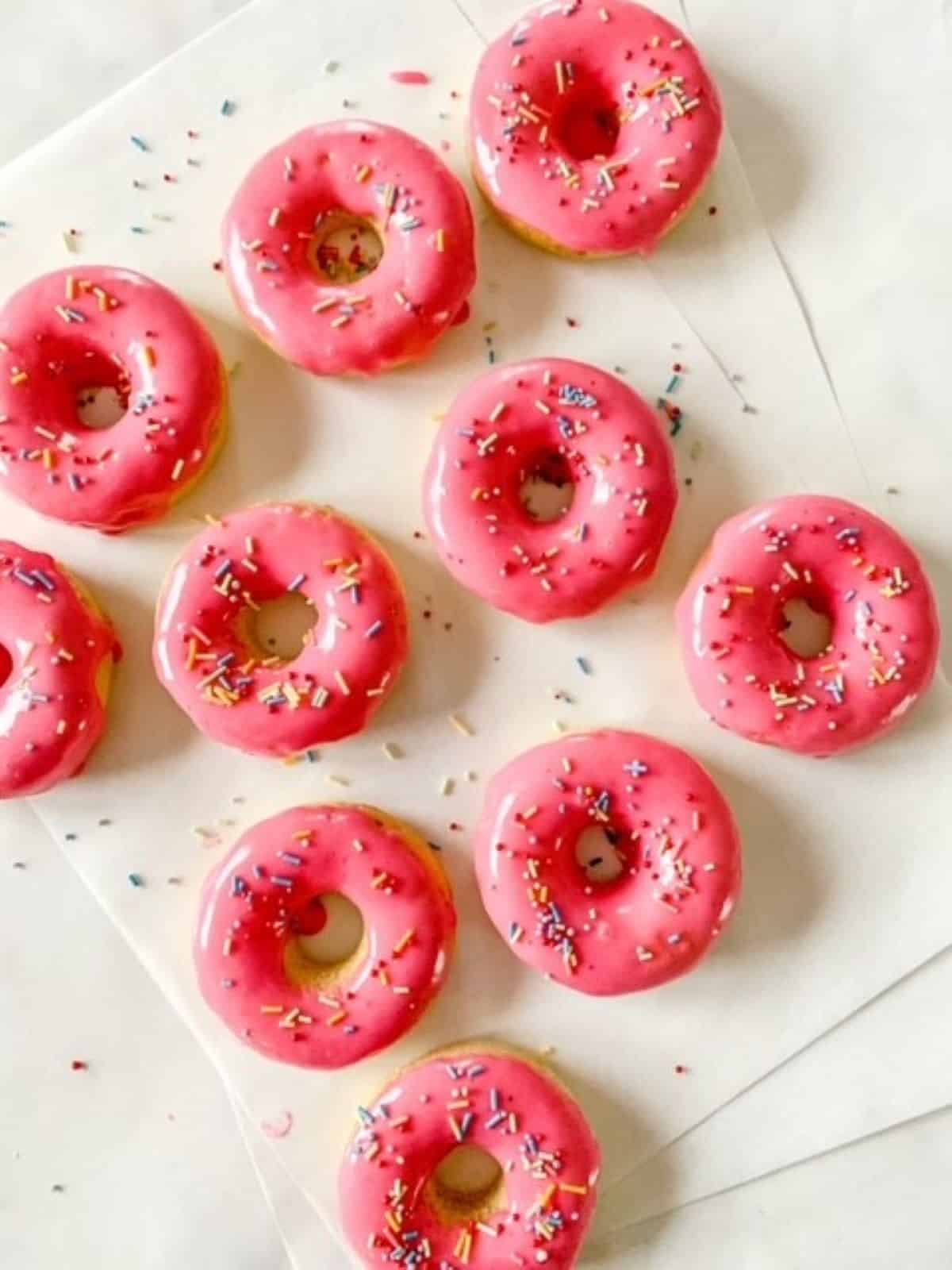 Pink glazed donuts on a white surface.