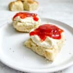 gluten free lemonade scones topped with whipped cream and jam on a white plate.