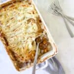 gluten free shepherds pie in a white baking dish with a serving spoon.
