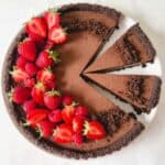 Oreo tart with two slices cut and strawberries on the side.