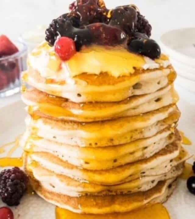 gluten free pancakes stack topped with fresh berries and syrup.