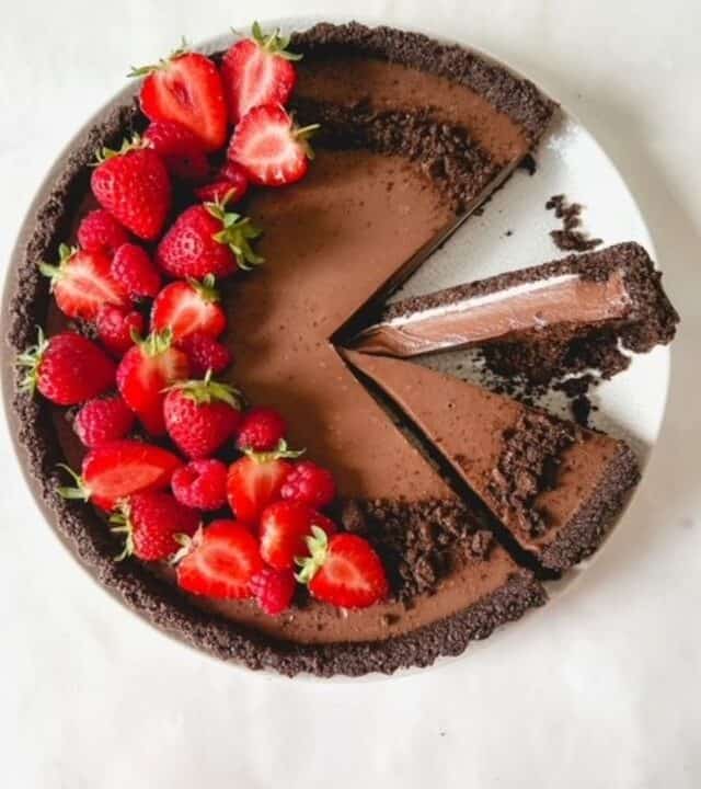 Oreo tart topped with strawberries with two slices cut into it.
