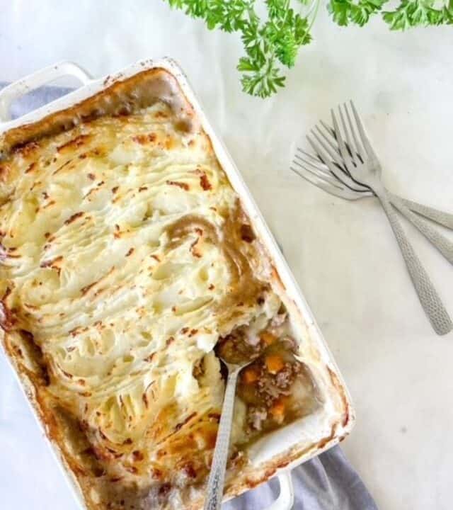 Shepherds pie in a white casserole dish with a large serving spoon.