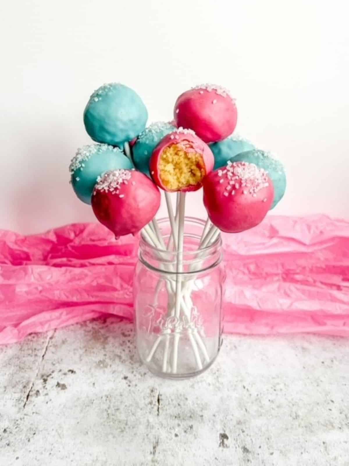 pink and blue gluten free cake pops in a clear jar.