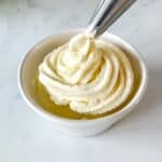 Crème Chantilly being piped into a small white bowl.