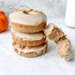 Gluten free Pumpkin donuts stacked beside a donut with a bite out of it.