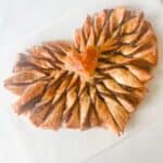 Heart shaped puff pastry with Nutella twists on a white surface.