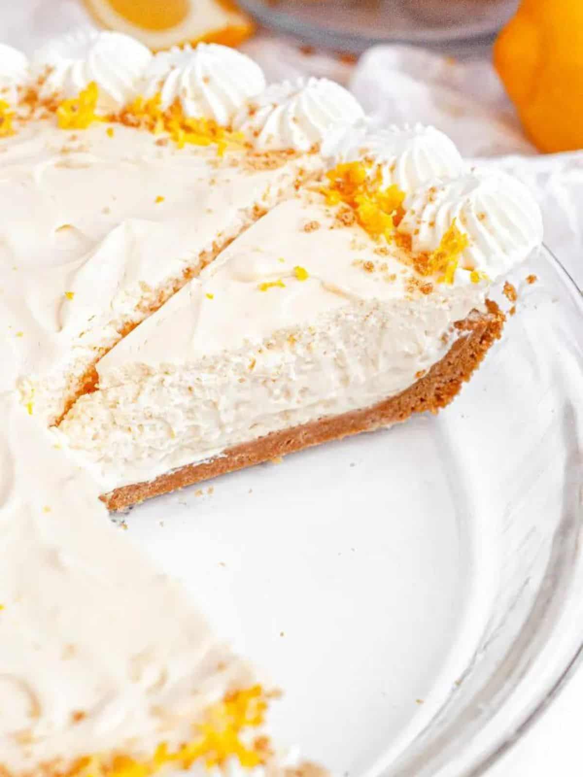 Lemon cheesecake in a clear pie dish with a few slices removed.