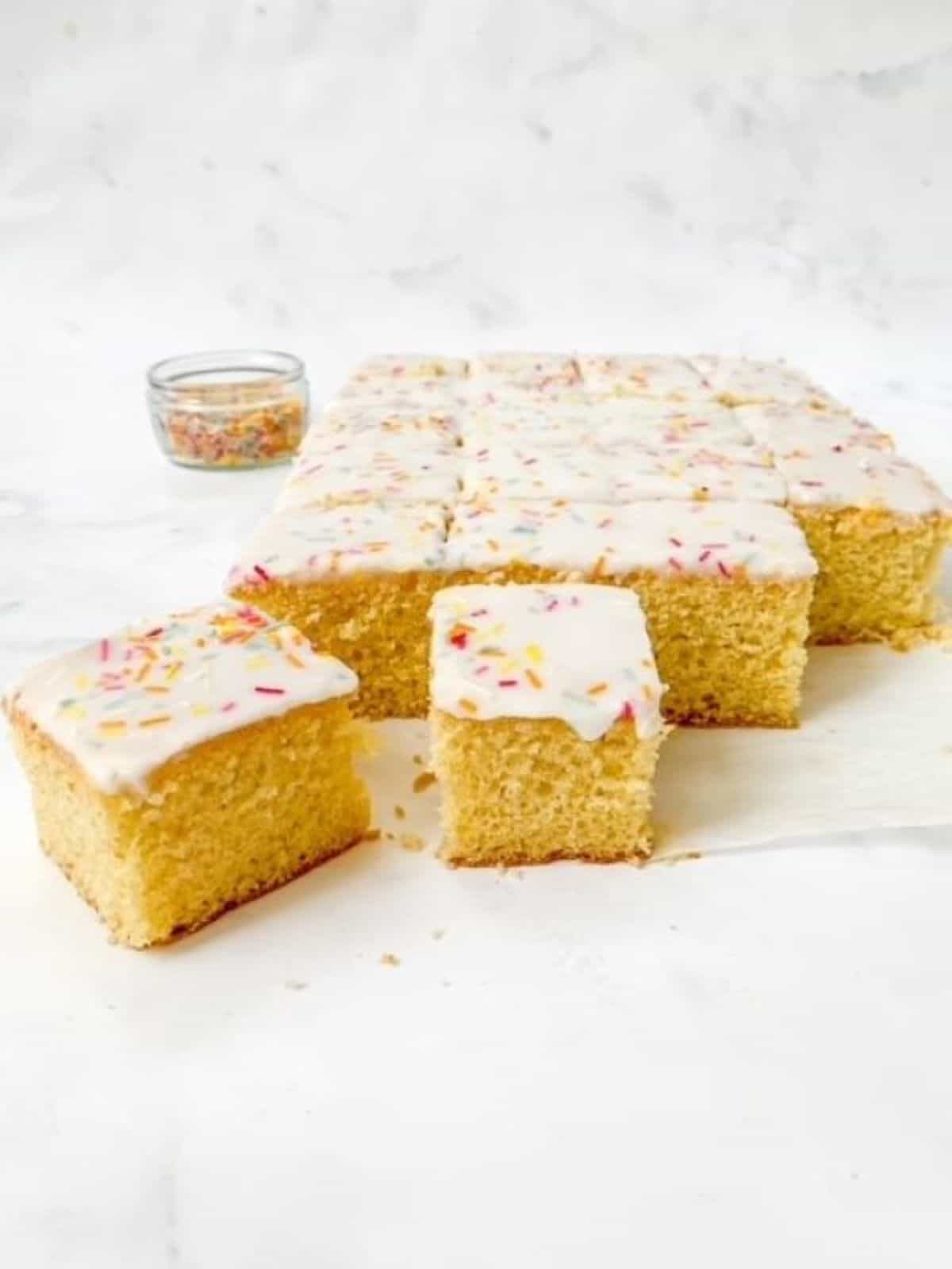 Sliced cake traybake on a white surface.