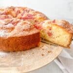 Close-up of rhubarb cake on a wooden cake stand.