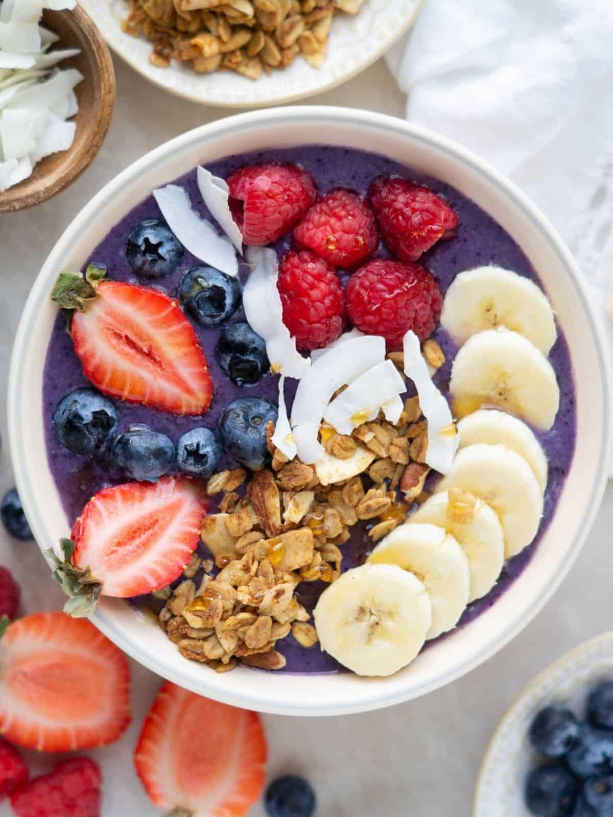 Breakfast smoothie in a white bowl topped with fresh sliced strawberries and bananas.