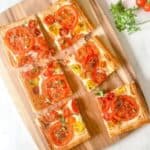 Tomato tarts on a wooden chopping board.