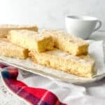 Gluten free shortbread stacked together on a silver serving plate on top of a tartan napkin.