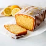 Gluten-free lemon drizzle cake sliced on a white background.