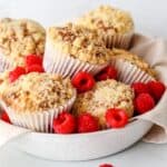 Gluten free raspberry and white chocolate muffins stacked together in a bowl.