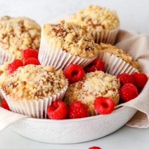 Gluten free raspberry and white chocolate muffins stacked together in a bowl.