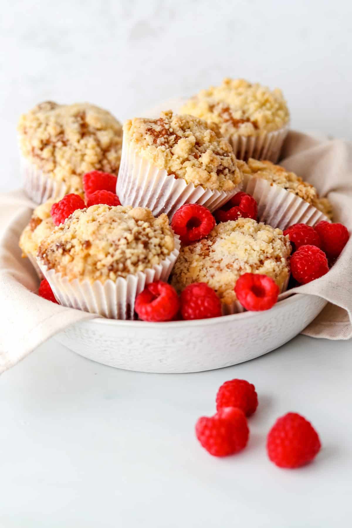 Gluten free raspberry and white chocolate muffins stacked together in a bowl.
