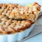 A slice of gluten free apple pie is being removed from the pie dish.