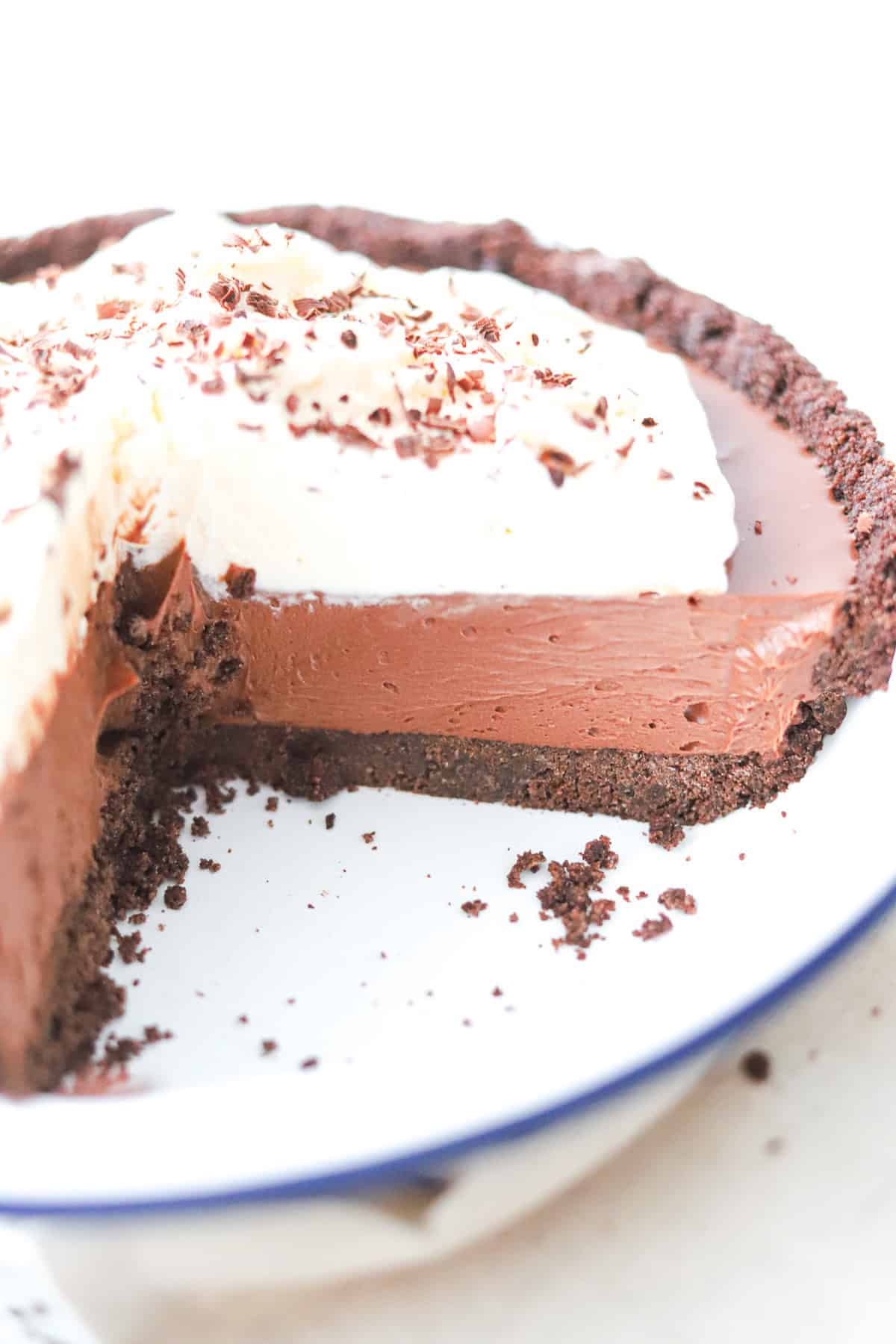 French silk pie in a white pie dish with a slice removed to reveal the filling.