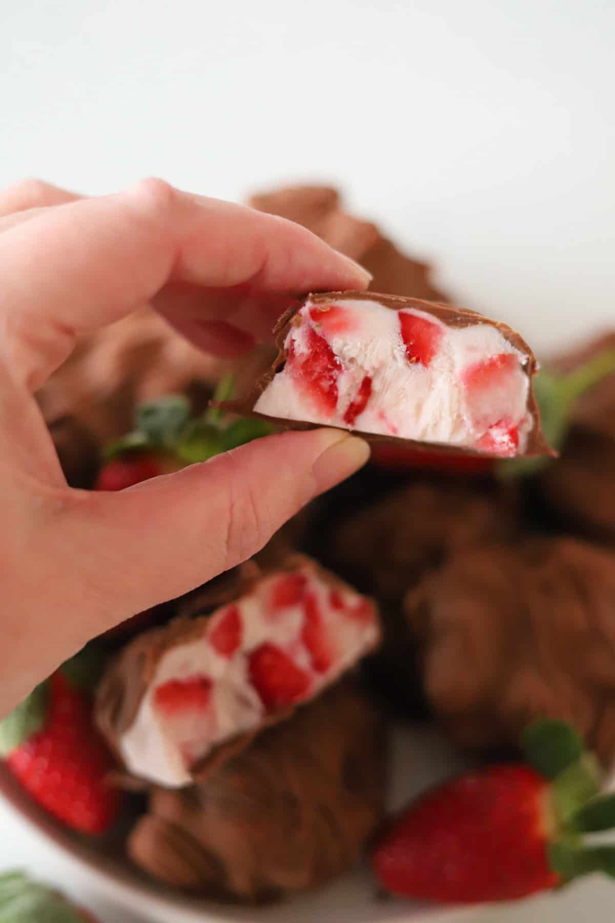 Hand holding a strawberry cluster.