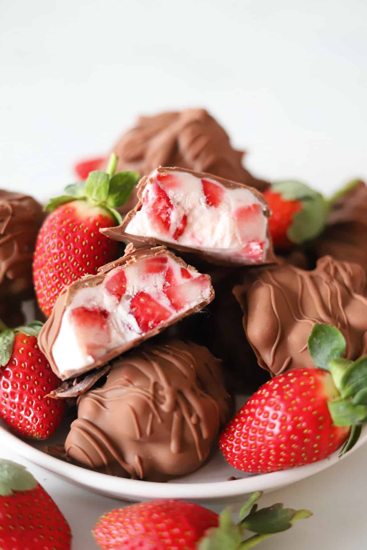 Chocolate strawberry yogurt clusters on a plate with one sliced in half to reveal the filling.