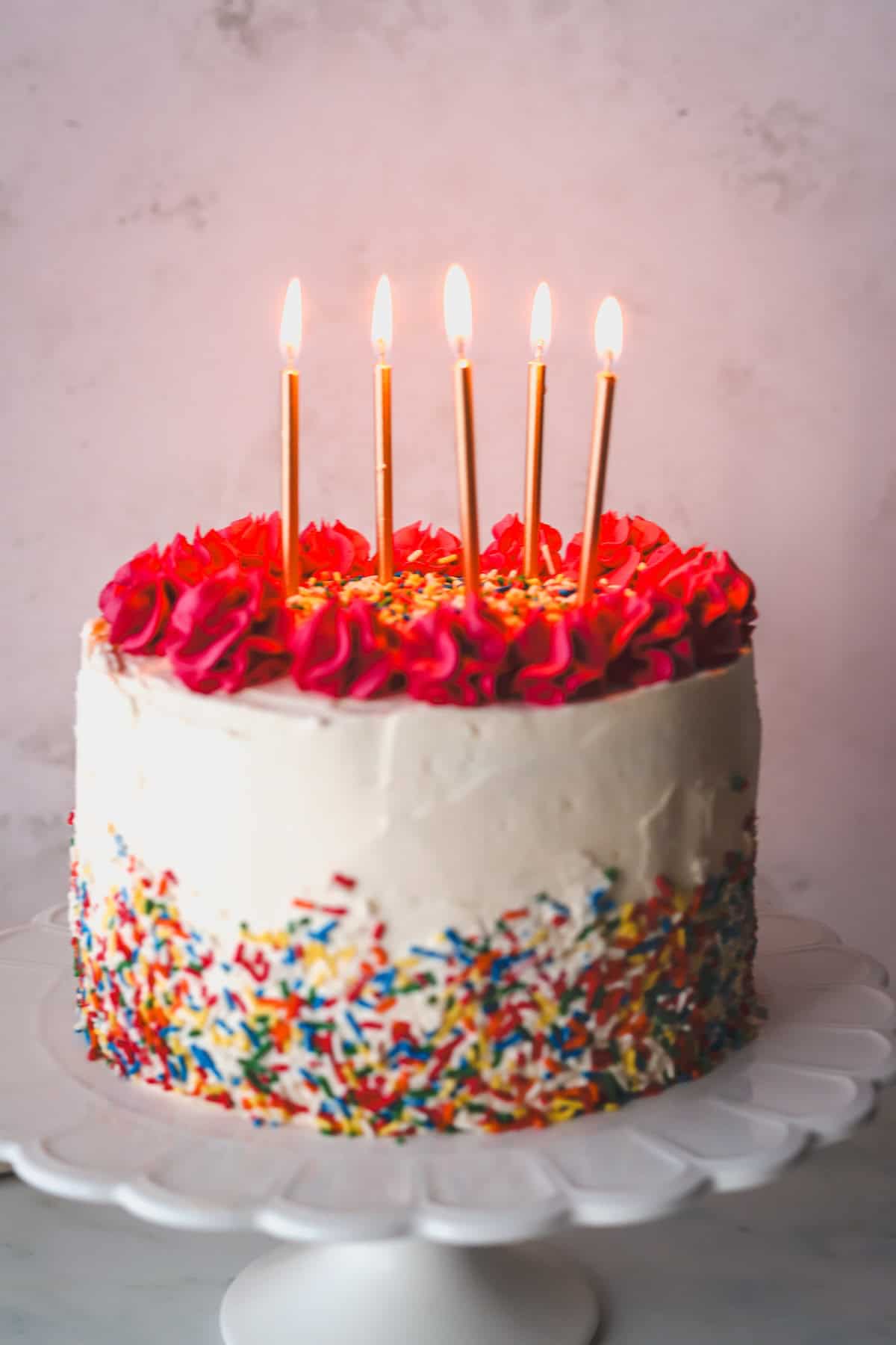 A gluten free birthday cake with sprinkles with birthday candles.