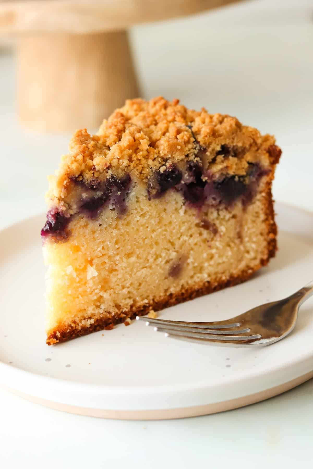 A slice of gluten free blueberry crumb cake on a white plate.